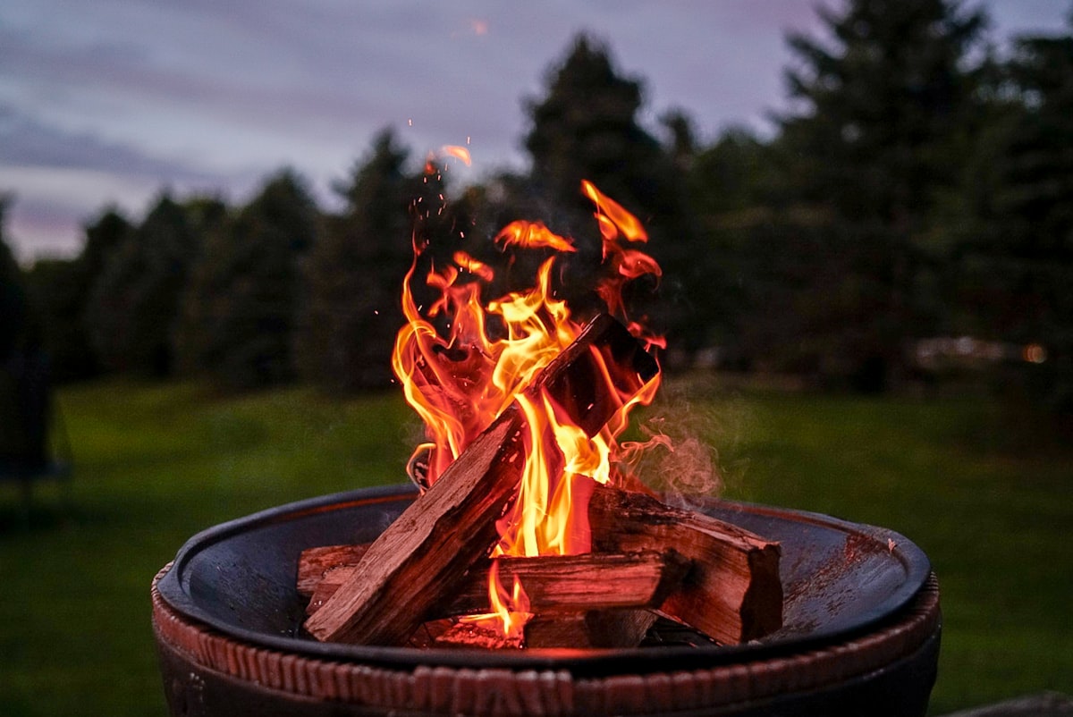 Backyard fire pit at dusk with Adirondack chairs surrounding it